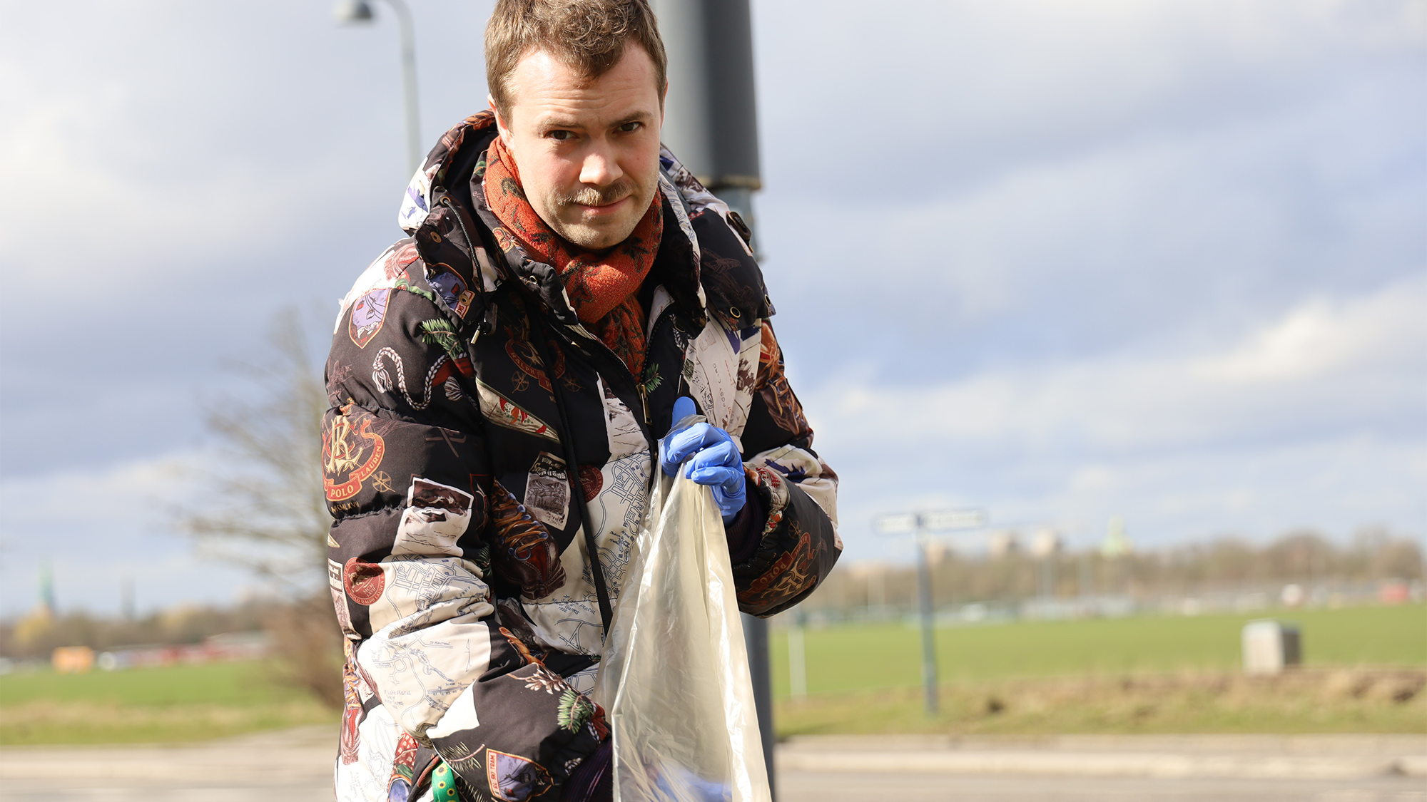 Ung mand med solsikkesnor samler affald ved Kløvermarken på Amager i anledning af affaldsindsamling på Kofoeds Skole 2023