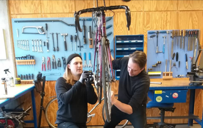 cykelmekaniker og mand reparerer cykel i cykelværksted på kofoeds skole
