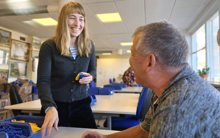 Kvindelig pædagogisk medarbejder instruerer bruger i værksted på Kofoeds Skole